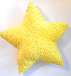 a yellow starfish pillow on a white background