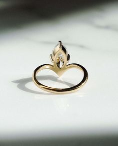 a gold ring with a heart shaped diamond in the center on a white table top