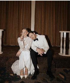 a bride and groom pose for a wedding photo in front of the stage at their reception