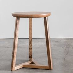 a small wooden table sitting on top of a cement floor next to a white wall