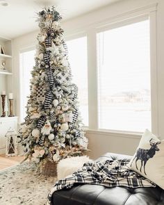 a decorated christmas tree in the corner of a living room with black and white decor