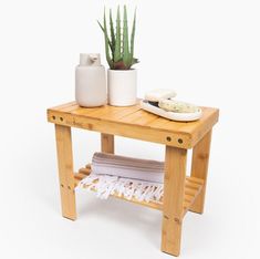 a small wooden table with two white vases on it and a towel next to it