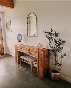 a wooden bench sitting next to a potted plant on top of a hard wood floor