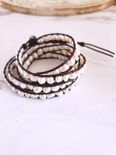 Beautiful genuine freshwater pearls are woven into these always on-trend leather pearl wrap bracelets. Wearing one of these bracelets will make you feel casually elegant since the pearls give a classy look to a traditionally bohemian style wrap bracelet. Choose from white pearls on natural tan leather or white pearls on dark brown leather. This pearl bracelet wraps around the wrist 5 times and is adjustable closure for flexible sizing. Bracelets are approximately 37 inches long and are adjustabl Elegant Multi-strand Adjustable Wrap Bracelet, Handmade Adjustable Luxury Pearl Bracelet, Elegant Handmade Adjustable Leather Bracelet, Handmade Elegant Leather Bracelet, Elegant Handmade Leather Bracelet, Elegant White Wrap Bracelet As Gift, Elegant White Wrap Bracelet For Gift, Elegant White Wrap Bracelet Gift, Chic Adjustable Pearl Bracelet