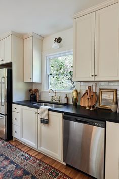 a kitchen with white cabinets and black counter tops, an area rug on the floor