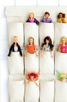 there are many barbie dolls in the pocket on this wall hanging from a towel rack