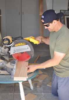 a man using a circular saw to cut wood with a mitt on top of a table