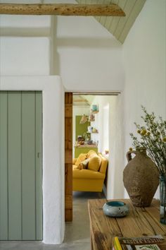 a living room filled with furniture next to a yellow couch and green door in the background