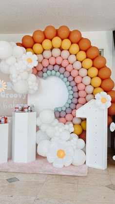 balloons are arranged in the shape of a rainbow on display at a baby's first birthday party