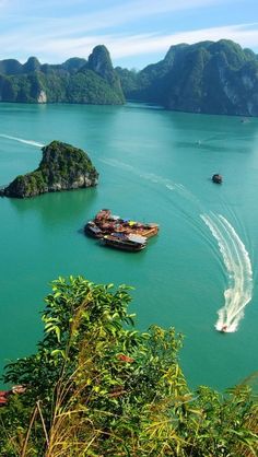 several boats traveling in the water near mountains