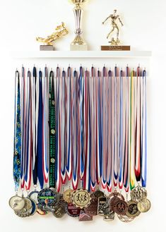 a bunch of medals are hanging on a wall next to a trophy and other trophies