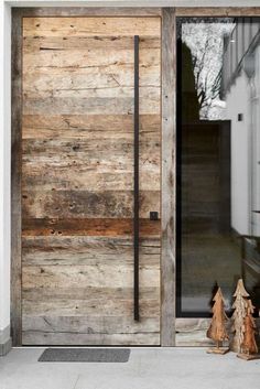 a wooden door with two small trees in front of it