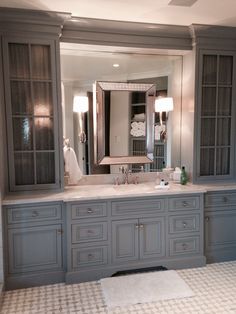 a large bathroom with gray cabinets and marble counter tops