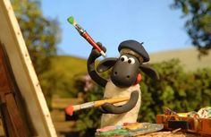 a toy sheep holding a paintbrush and wearing a hat