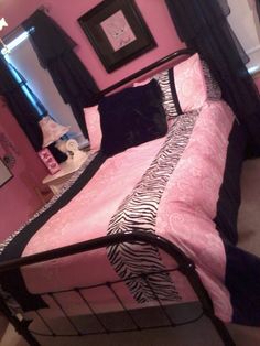 a pink and black bedroom with zebra print bedding