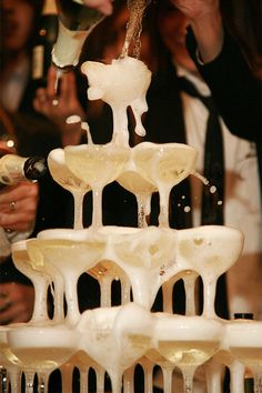 a group of people standing around a table with wine glasses on top of each other