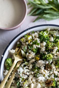 a bowl filled with rice and broccoli next to a spoon