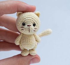 a small crocheted cat sitting in someone's hand