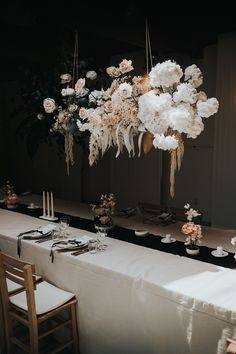 a long table is set with white flowers and place settings for an elegant dinner party