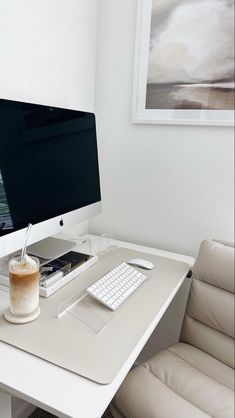 a white desk with a computer monitor, keyboard and mouse next to a cup of coffee