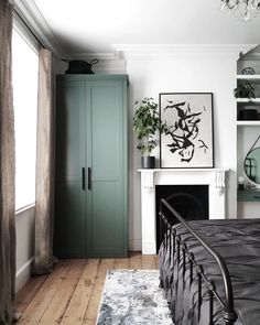 a bedroom with a bed, fireplace and green cupboards on the wall in front of it