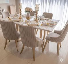 a dining room table with chairs and plates on it