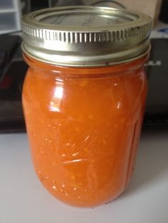 a jar filled with orange liquid sitting on top of a table