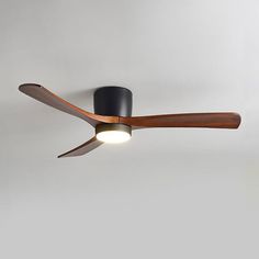 a ceiling fan with a wooden blade and light on the top, in front of a white wall