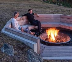 two men sitting on benches around a fire pit