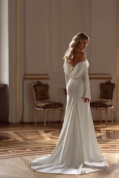 a woman in a white wedding dress standing on the floor with her back to the camera