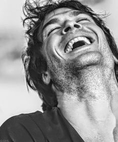 a black and white photo of a man with his hair blowing in the wind, looking up