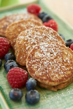 pancakes with berries and powdered sugar on a green plate