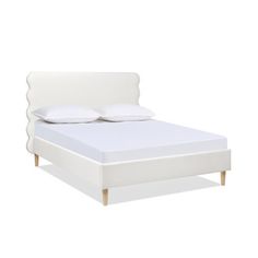 the bed is made up with white sheets and pillows on it's headboard