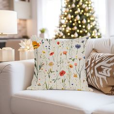 a living room with a christmas tree in the background and pillows on the couches