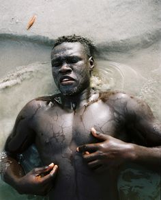 a man with mud all over his body and hands on his chest in the water