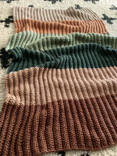 four knitted sweaters laying on top of a white and black rug next to each other