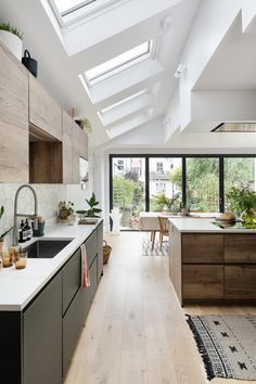 A modern timeless open plan kitchen and dining design with an island. Natural light pouring in from skylights and a  large bi-fold aluminium doors opening to the garden. Wooden flooring connects the spaces kitchen and dining from the hallway. Kitchen quarts worktop, with large green and oak finish drawers. The two tone kitchen design  creates a harmonious atmosphere the space and reflects the outside in. Modern Kitchen Extensions, Modern Kitchen Dining, Painting Kitchen, Kitchen Runner Rug, Uk Kitchen, Kitchen Runner, Stunning Kitchens