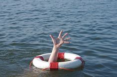 a person floating in the water on top of a life preserver with their hand out