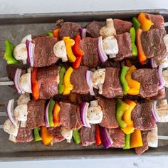 skewered meat and vegetables on a tray ready to be cooked in the oven