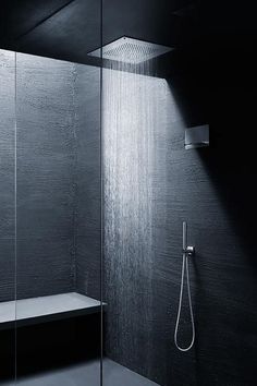 a black and white photo of a shower in a bathroom with glass walls, the shower head is open