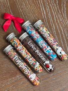 five jars with different colored confetti on them and a red ribbon tied to the top