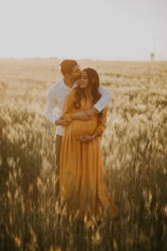 a man and woman standing in a wheat field