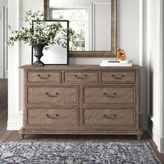 a dresser with a mirror and vase on top