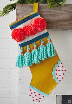 a christmas stocking hanging from a fireplace with pom - poms on it