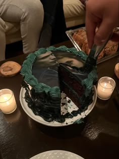 a person cutting a piece of cake with a knife on a table next to candles