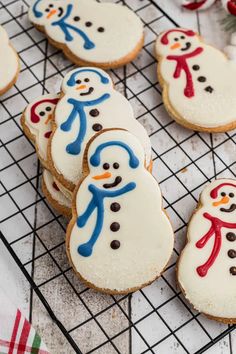 frosted cookies decorated like snowmen on a cooling rack