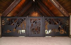 two metal gates with deers and trees on them in an open space that has carpeted flooring