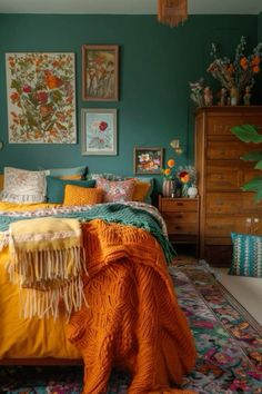 a bedroom with green walls and orange blankets on the bedspread is decorated with colorful flowers