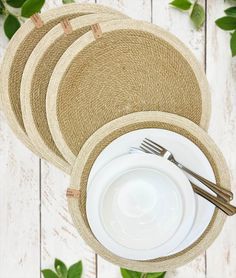 three place mats with forks and spoons in them on a white wooden table top