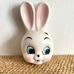 a white ceramic bunny mask with blue eyes